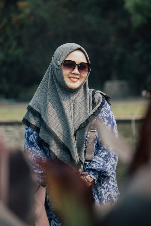 Photo of a Smiling Woman Wearing a Headscarf and Sunglasses