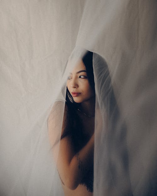 Young Woman Posing in between Sheer Fabric 