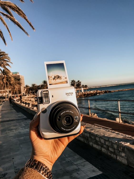 Persona In Possesso Di Instax Mini 70 Vicino Al Mare