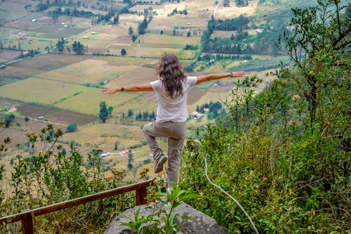 Woman Standing on One Leg with Outstretched Arms and Looking at Landscape