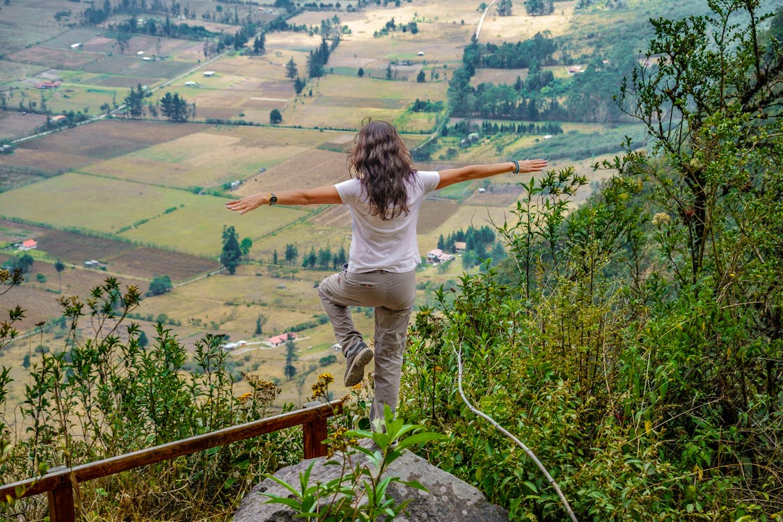 Woman Standing on One Leg with Outstretched Arms and Looking at Landscape