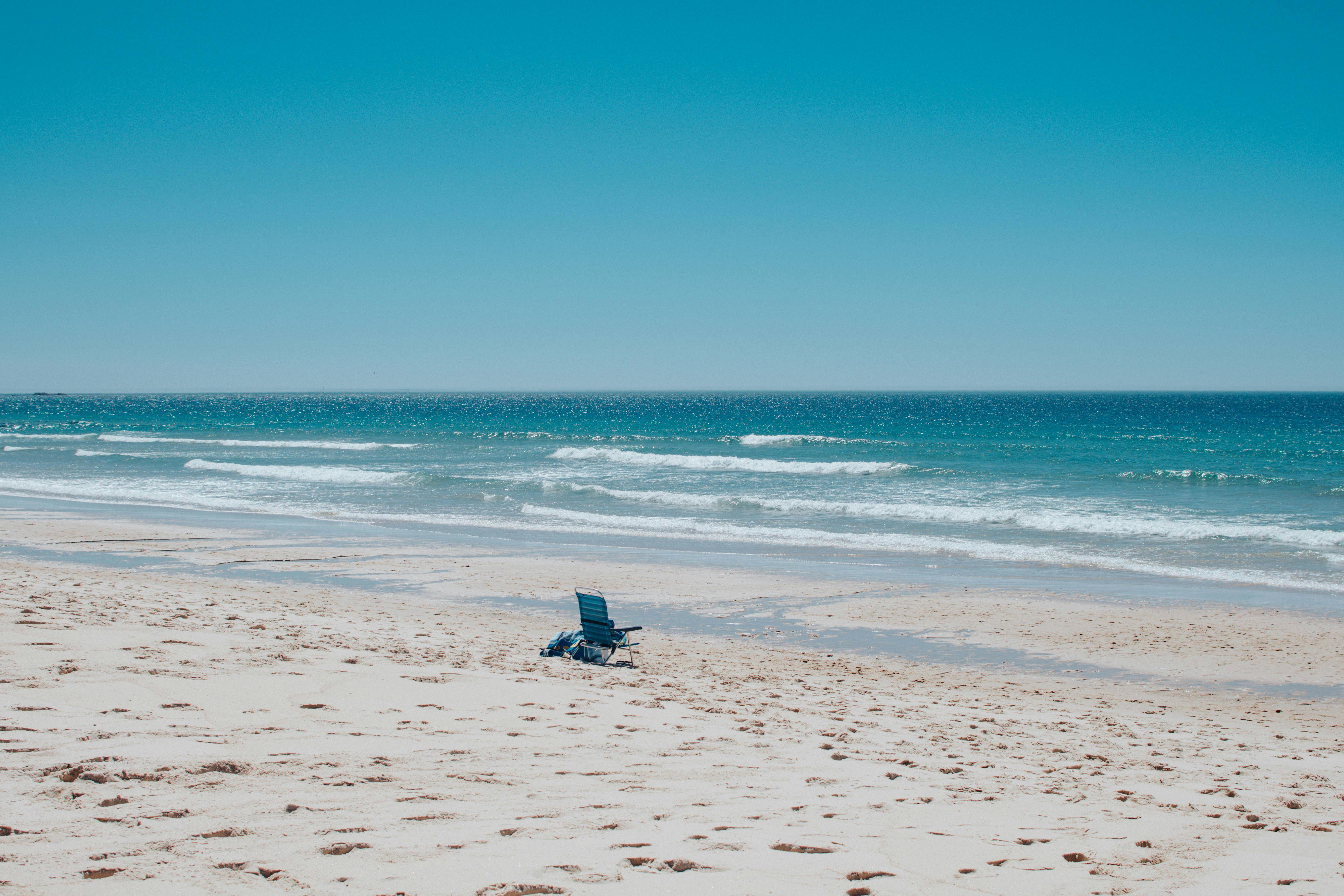 A lone blue chair facing the serene ocean on Portosín beach, Spain
