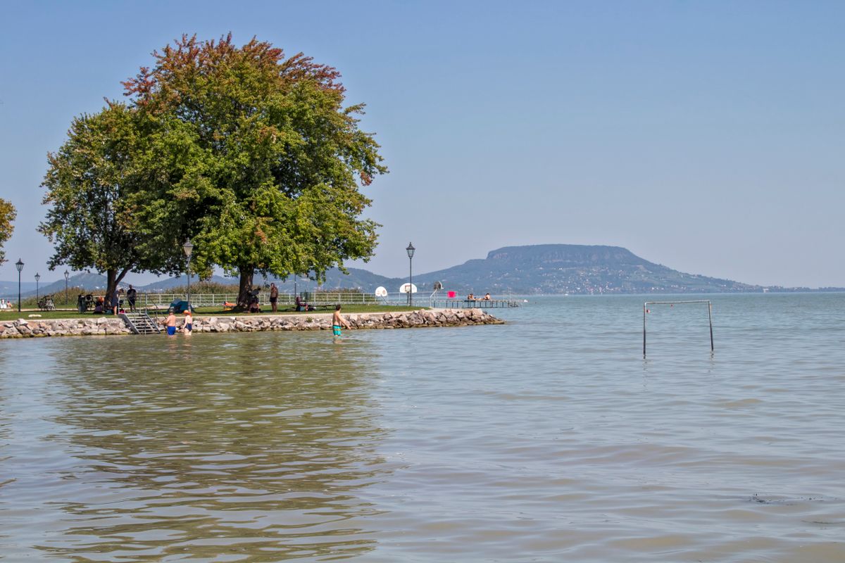 Malul lacului Balaton cu apă puțin adâncă și dealul Badacsony ridicându-se în fundal