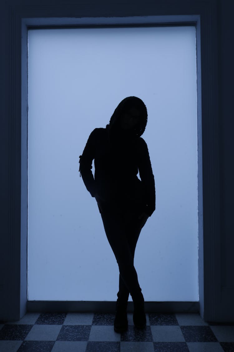 Silhouette Of Person Standing Against Blue Light