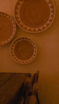 Warm toned room featuring artistic hanging woven plates and rustic furniture.