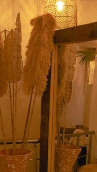 A cozy indoor decor setup with rattan elements, vases, and a large mirror reflecting soft lighting.