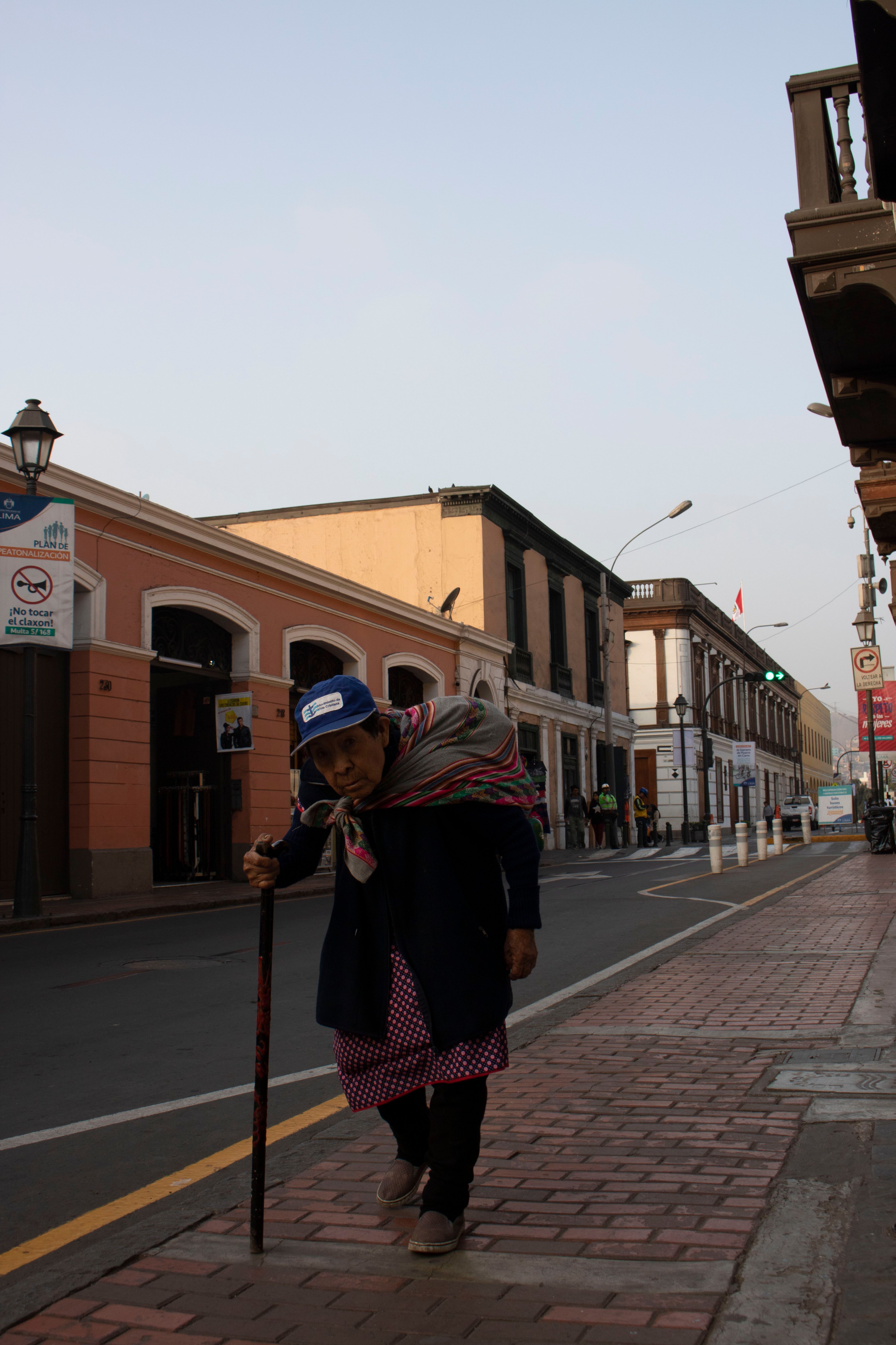 Mujer mayor caminando con bastón por una acera, símbolo de la pérdida de equilibrio en la sarcopenia