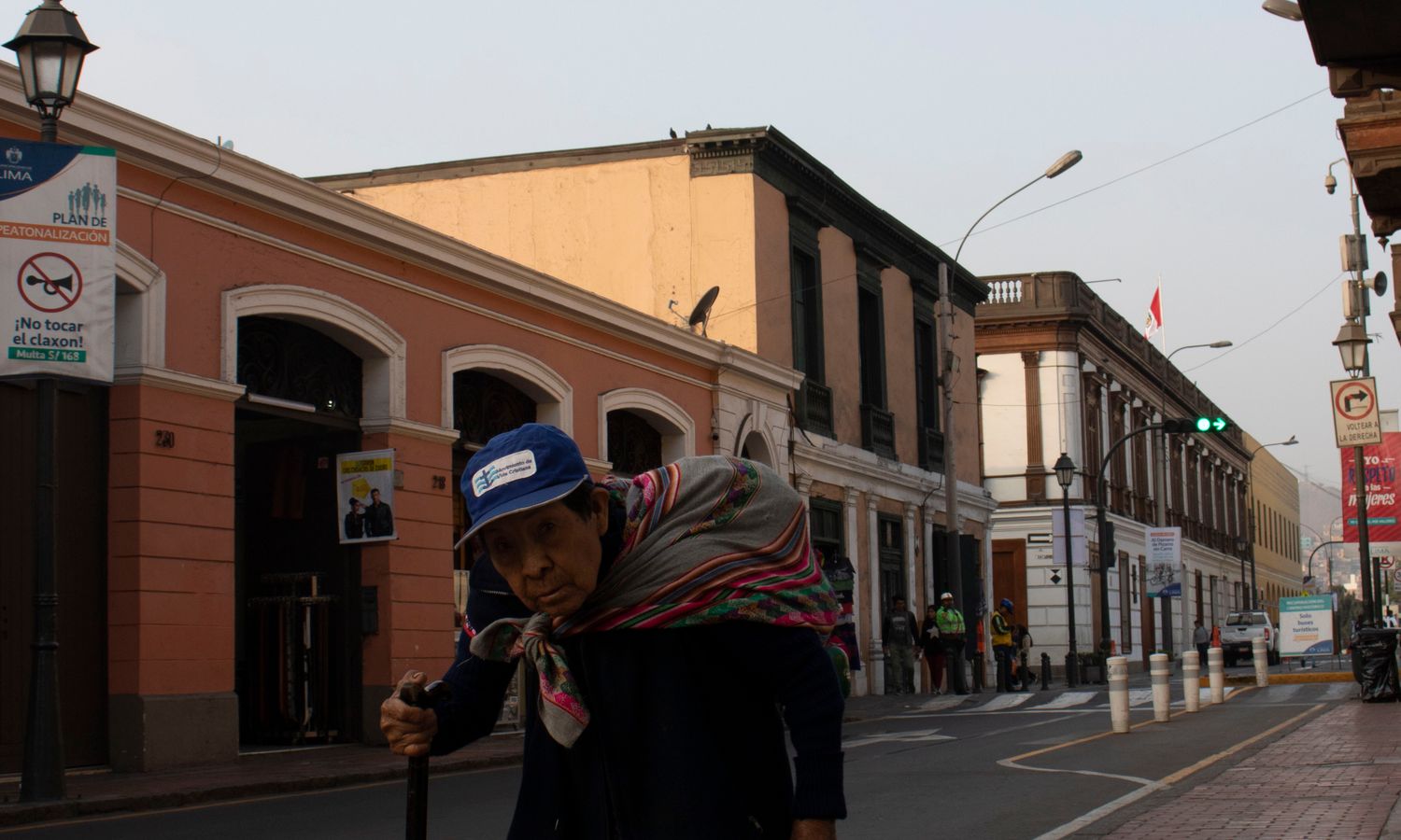 Mujer mayor caminando con bastón por una acera, símbolo de la pérdida de equilibrio en la sarcopenia