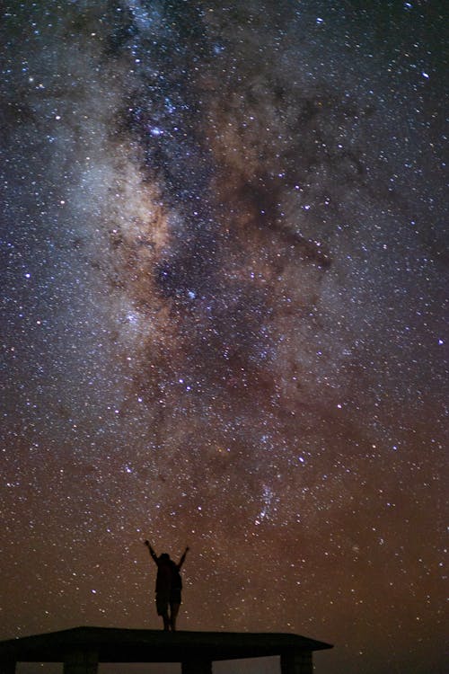 Night Sky with Stars over Person Standing with Arms Raised