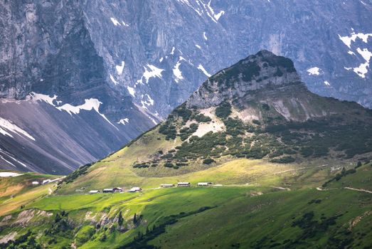 Beautiful alpine landscape featuring a serene mountain valley with lush greenery and rustic huts.