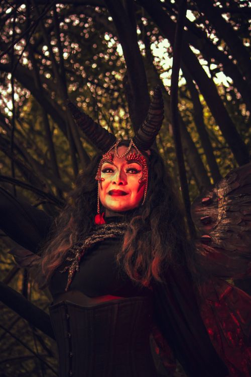 Free A captivating portrait of a woman in a devil costume with horns in a forest setting. Stock Photo
