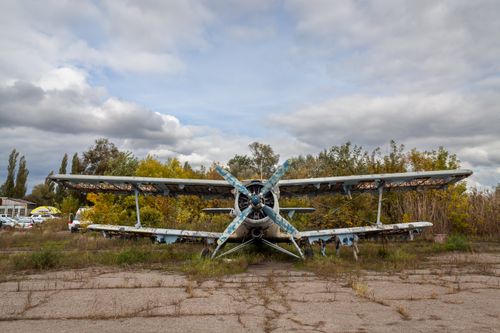 Free A decaying biplane rests amidst the overgrown foliage of Enem, Russia. Stock Photo