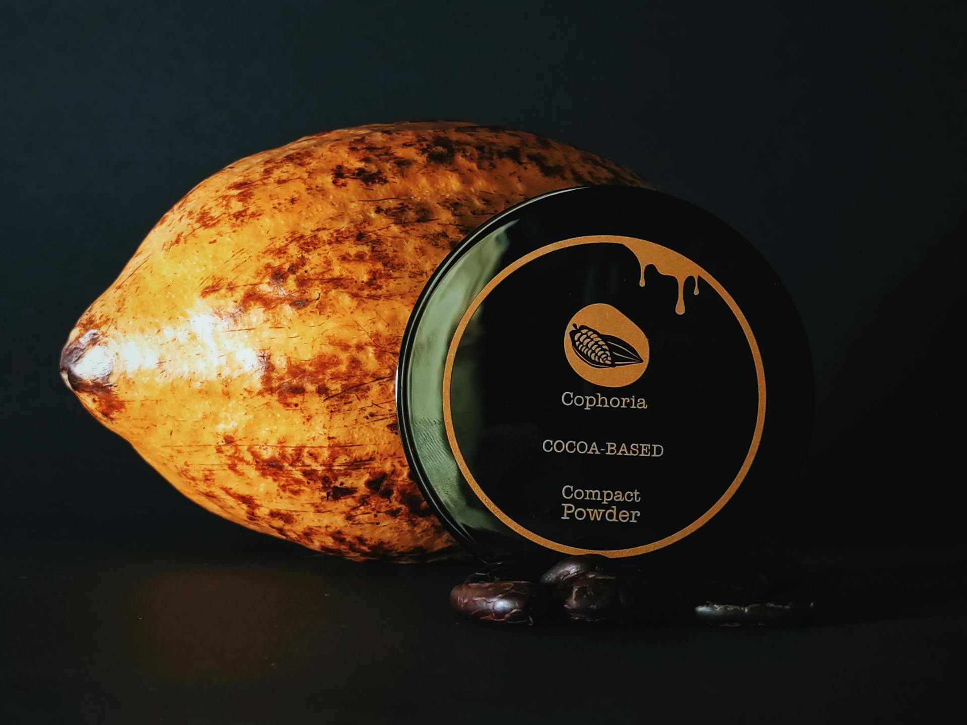 A vibrant cocoa bean with Cophoria cocoa-based compact powder on a dark background highlighting natural beauty products.