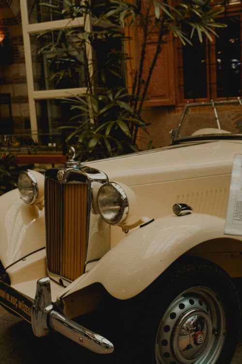 Free Classic MG TD car showcasing 1950s design in a warm indoor setting with plants. Stock Photo