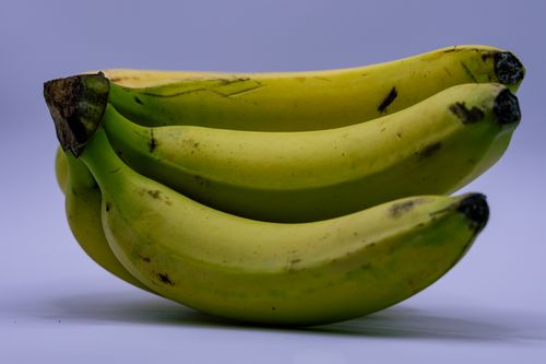 Free A close-up image of a bunch of ripe bananas on a plain background, showcasing their fresh appearance. Stock Photo
