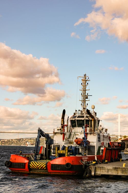Free A bright red tugboat moored at the dock in Istanbul with scenic background. Stock Photo