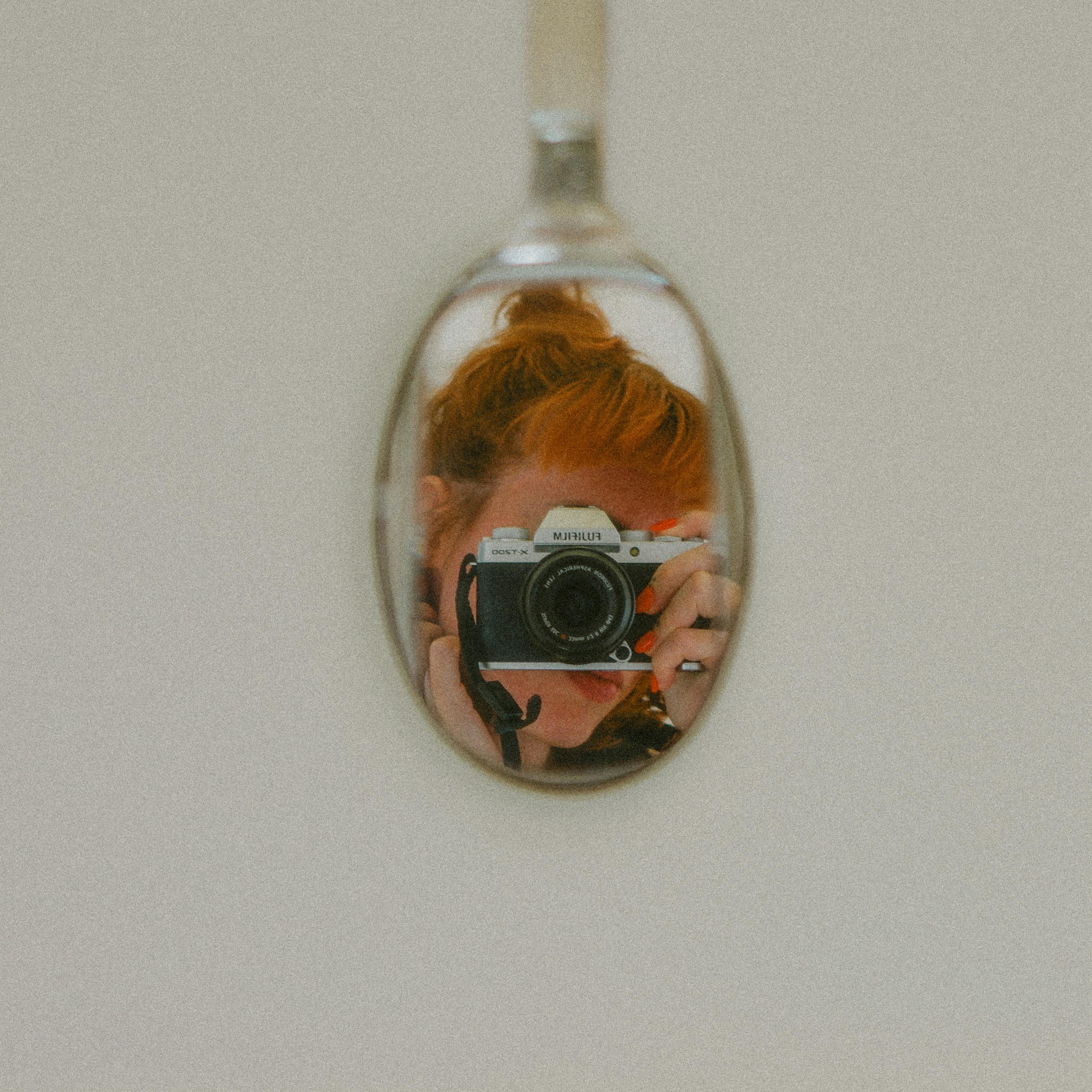 A photographer captures a self-portrait using a reflective spoon surface.