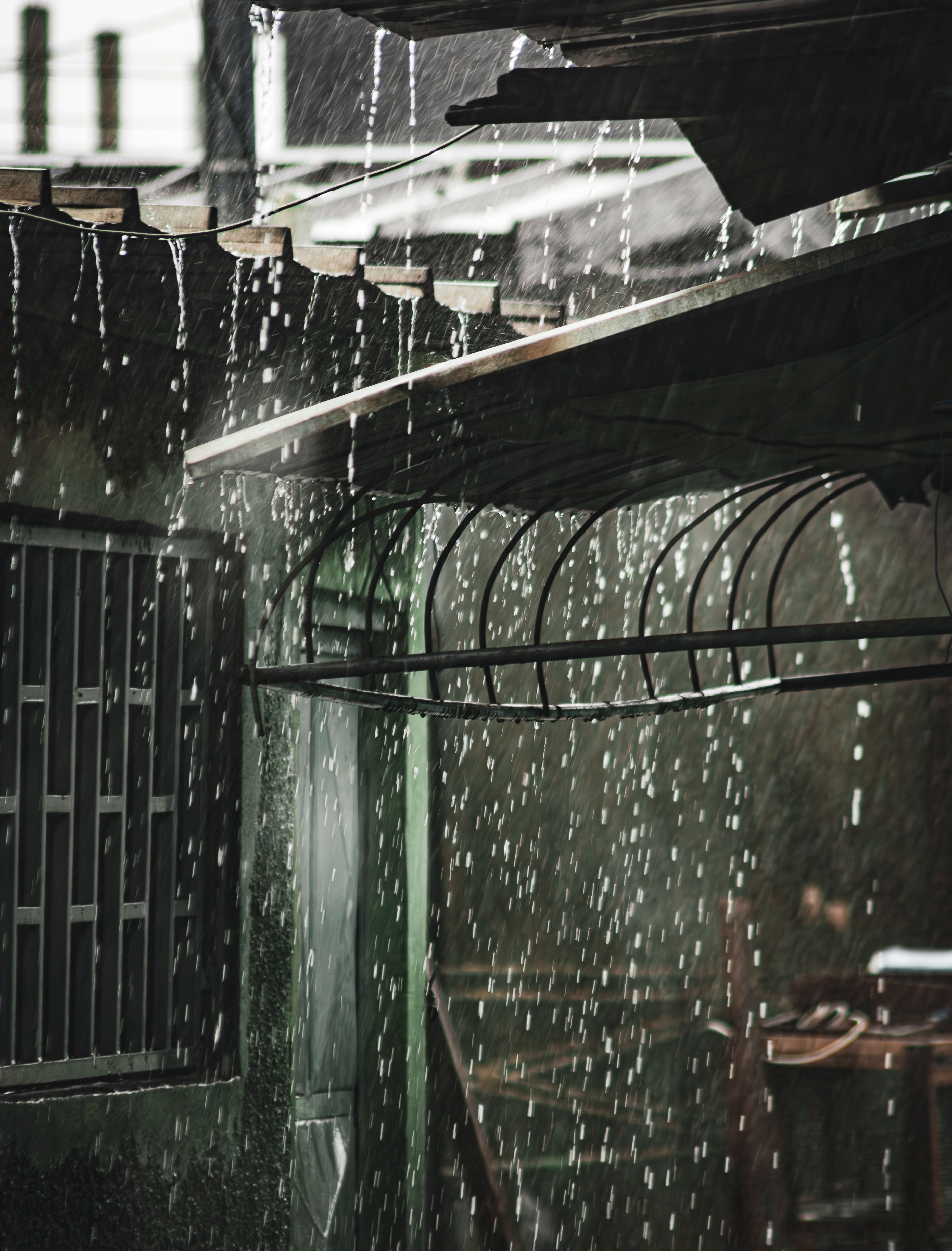 Heavy rain pouring off a roof edge during a storm