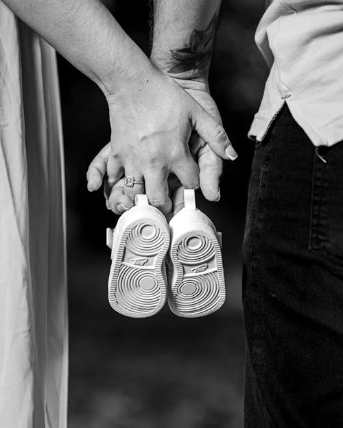Couple Holding Hands and Baby Shoes