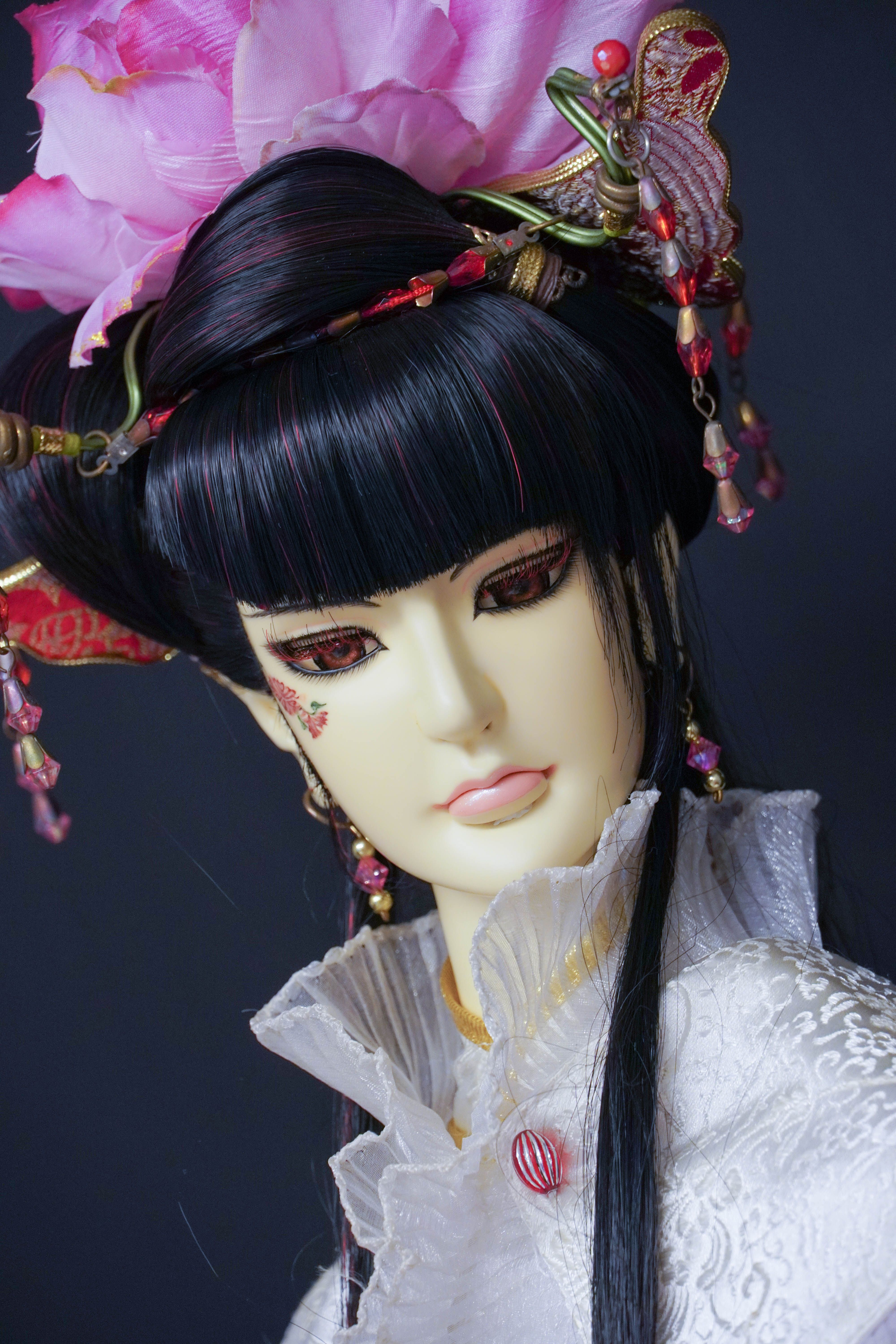 Close-up shot of a beautifully decorated doll with a floral headpiece against a black background.