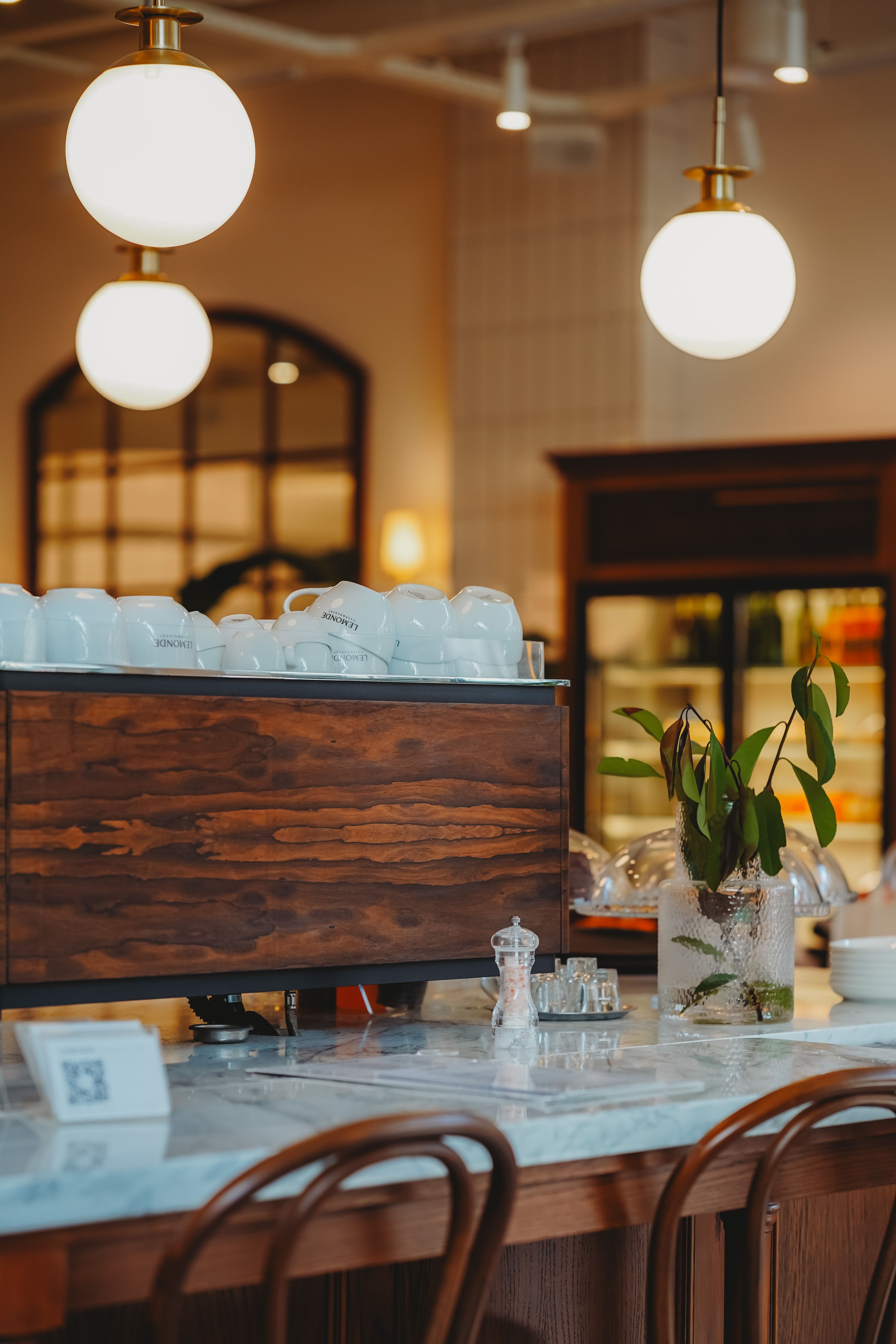 Wooden tables and warm pendant lamps inside the front room of Hearth and Oak Café