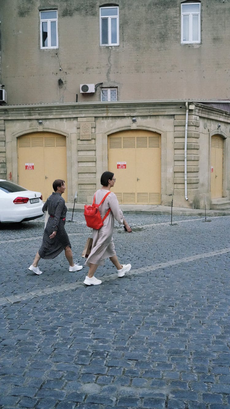 Pedestrians Crossing The Cobblestone Street