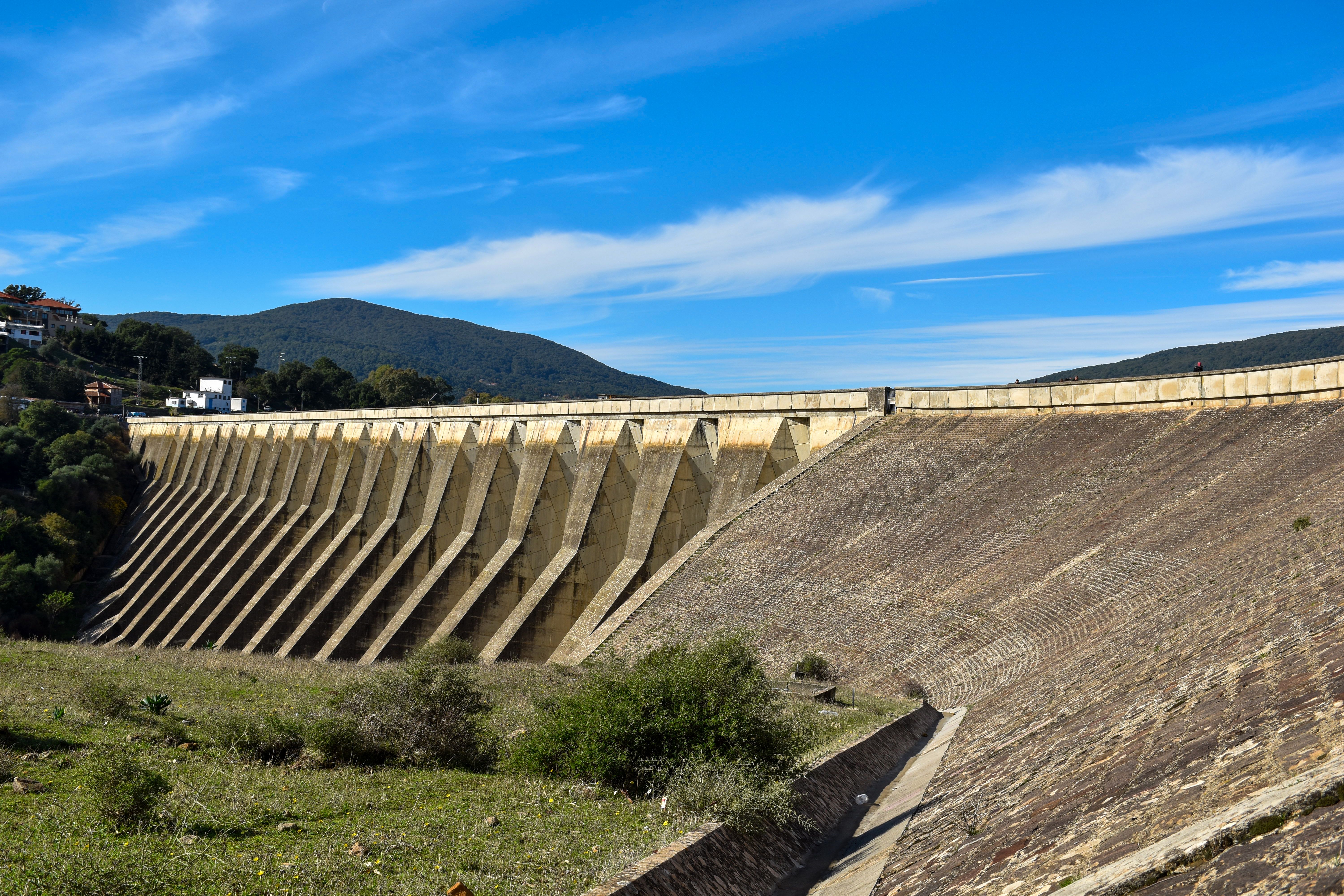 A stunning view of a massive concrete dam set against a vibrant blue sky, showcasing renewable energy infrastructure.