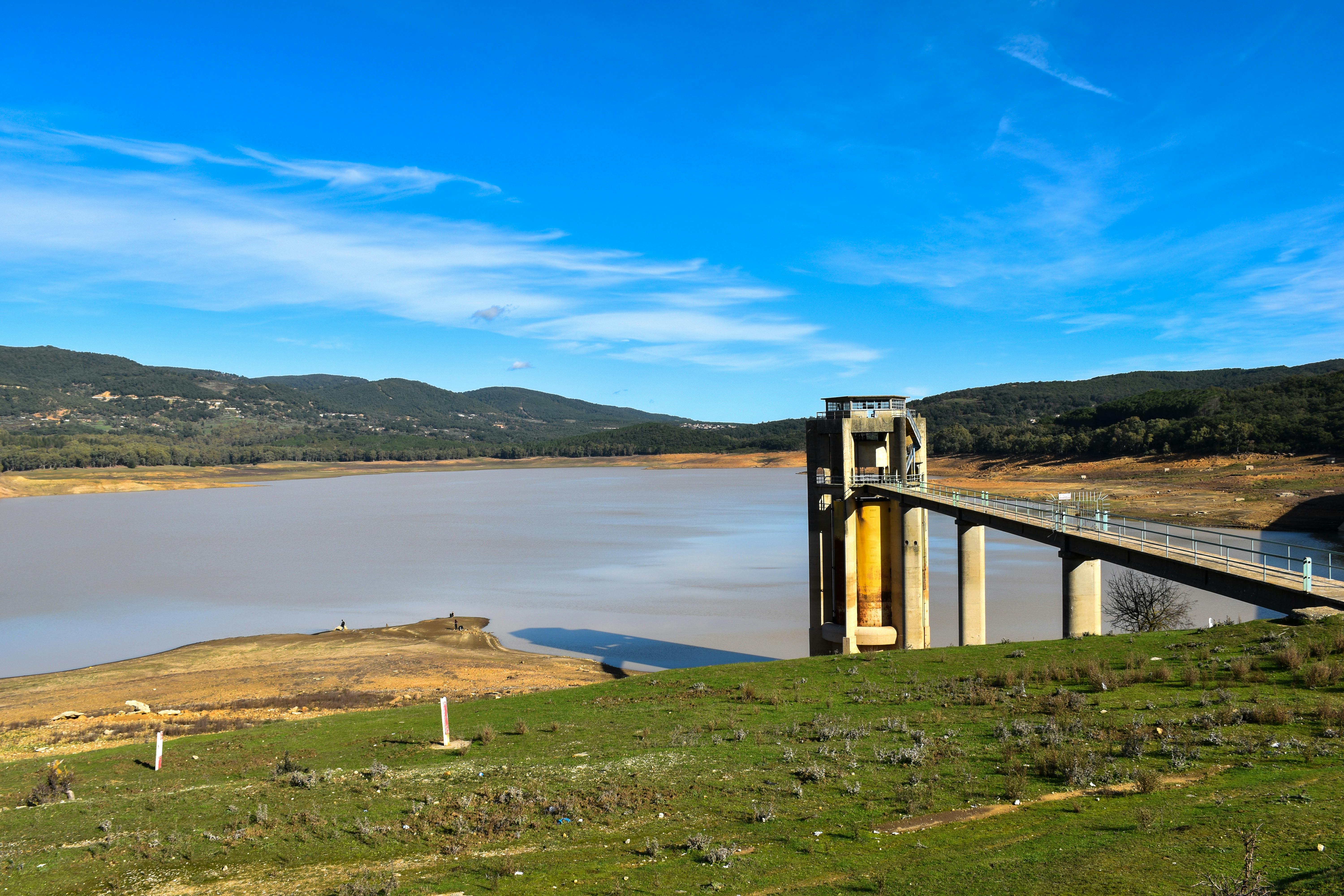 Scenic view of Beni M'Tir Dam and reservoir surrounded by hills under a clear blue sky.