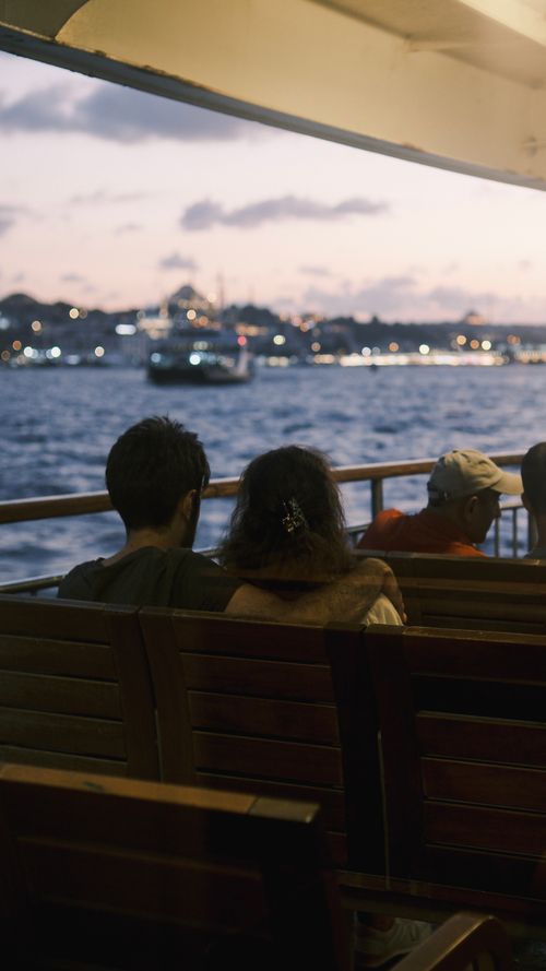 Free Couple enjoying a romantic evening ferry ride at sunset with city lights in the background. Stock Photo