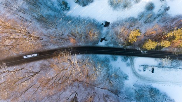Aerial shot of a snow-covered road cutting through a forest in Wejherowo, Poland.