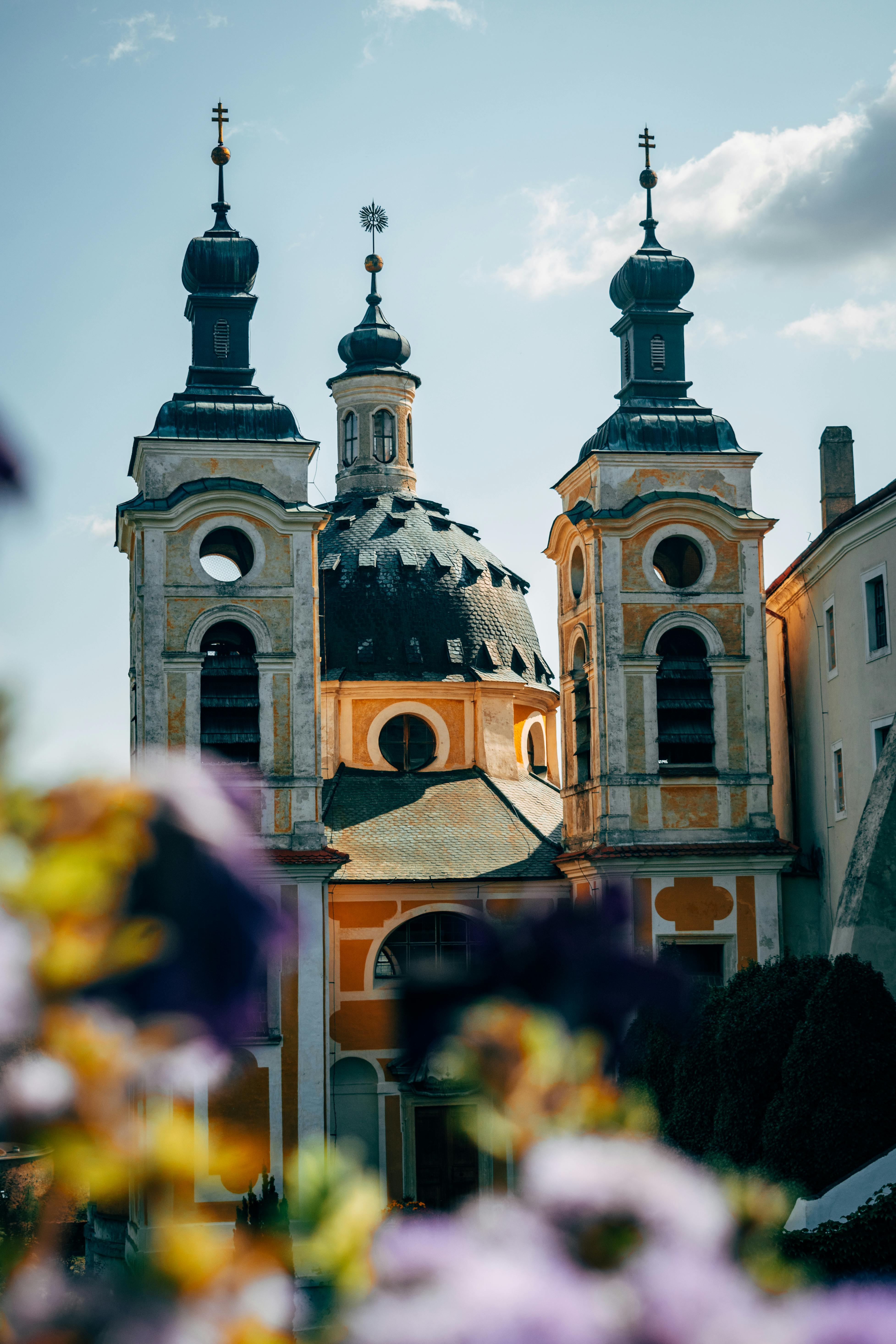 一座拥有双子塔和圆顶的巴洛克式教堂令人惊叹，在白天明亮的天空下，四周鲜花环绕
