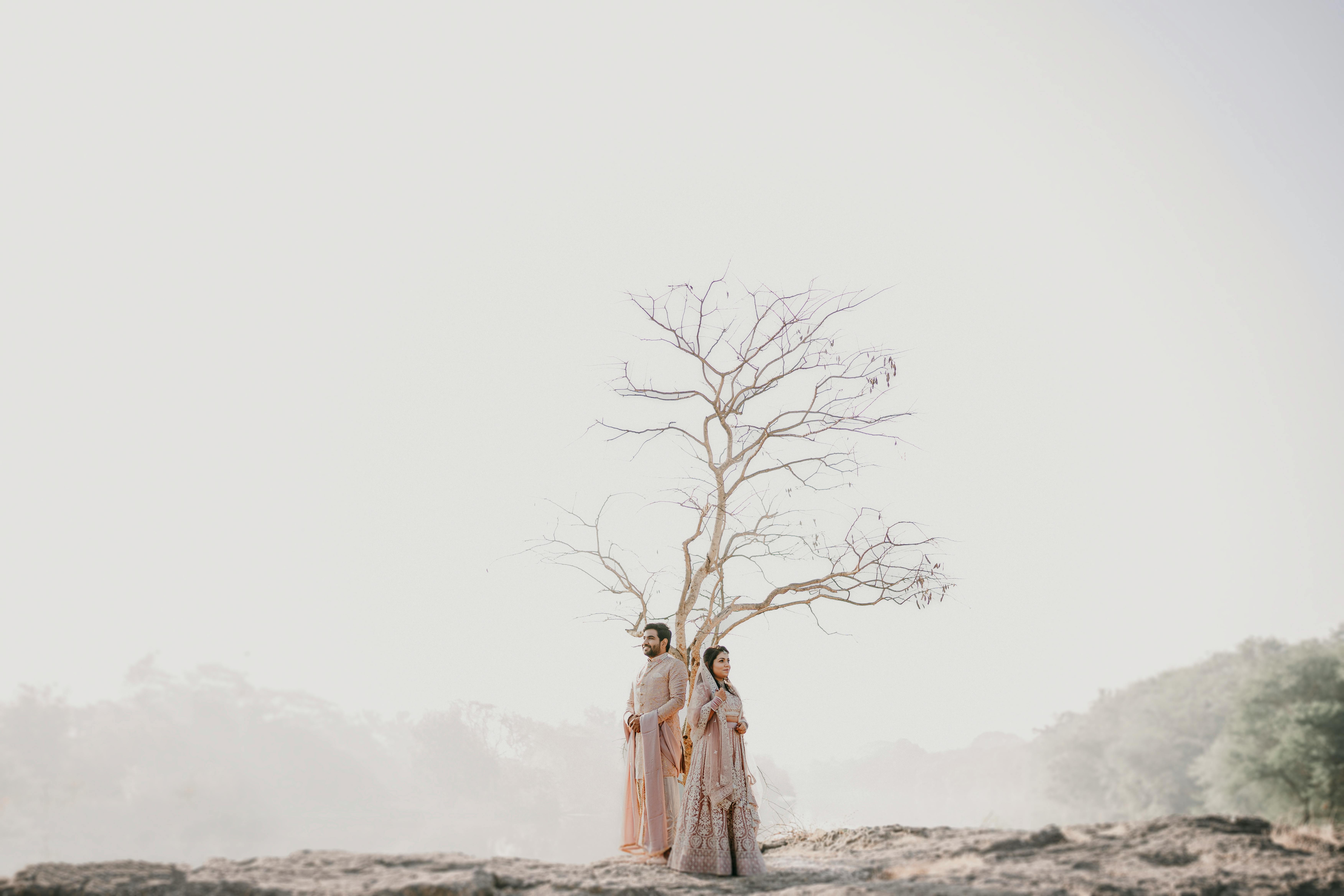 A beautifully captured Indian wedding couple in traditional attire standing outdoors by a tree in Pune, India.