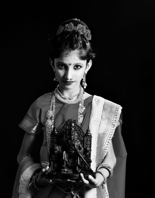 Free Black and white portrait of a young Indian woman in traditional attire holding a sculpture, showcasing cultural elegance. Stock Photo