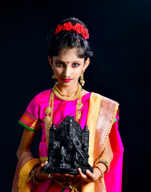 Woman in Traditional Clothing Holding Statue