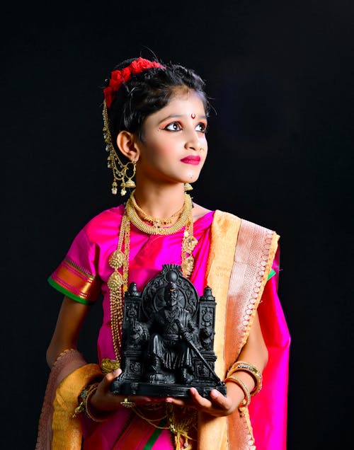 Woman Standing in Traditional Clothing and Holding Statue