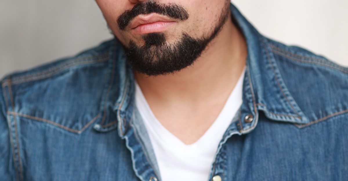 Photo by Salvador Olague Portrait of a man with a strong gaze wearing a denim jacket, featuring a clean white background.
