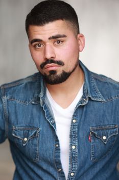 Photo by Salvador Olague Portrait of a man with a strong gaze wearing a denim jacket, featuring a clean white background.