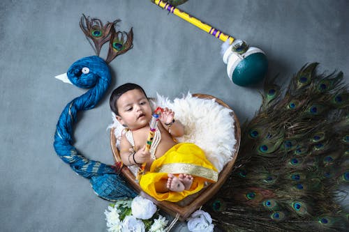 Baby Boy Lying Down in Bed in Heart Shape and with Peacock around