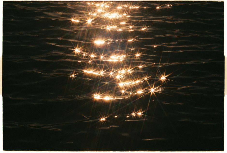 Golden sunlight sparkles on the rippling water surface, creating a magical serene atmosphere.