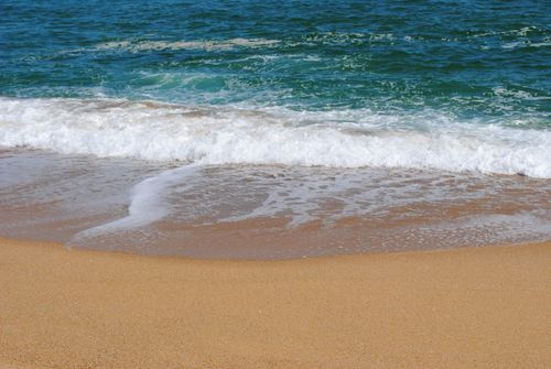 Free Sandy beach with gentle ocean waves, ideal for summer relaxation and nature lovers. Stock Photo