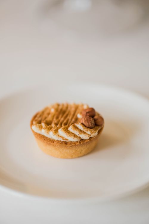 Free Delicious almond-topped cupcake on a white plate, ideal for food lovers. Stock Photo