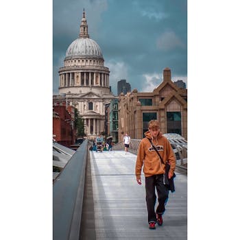 Tourists strolling on London's Millennium Bridge with St. Paul's Cathedral in the background.