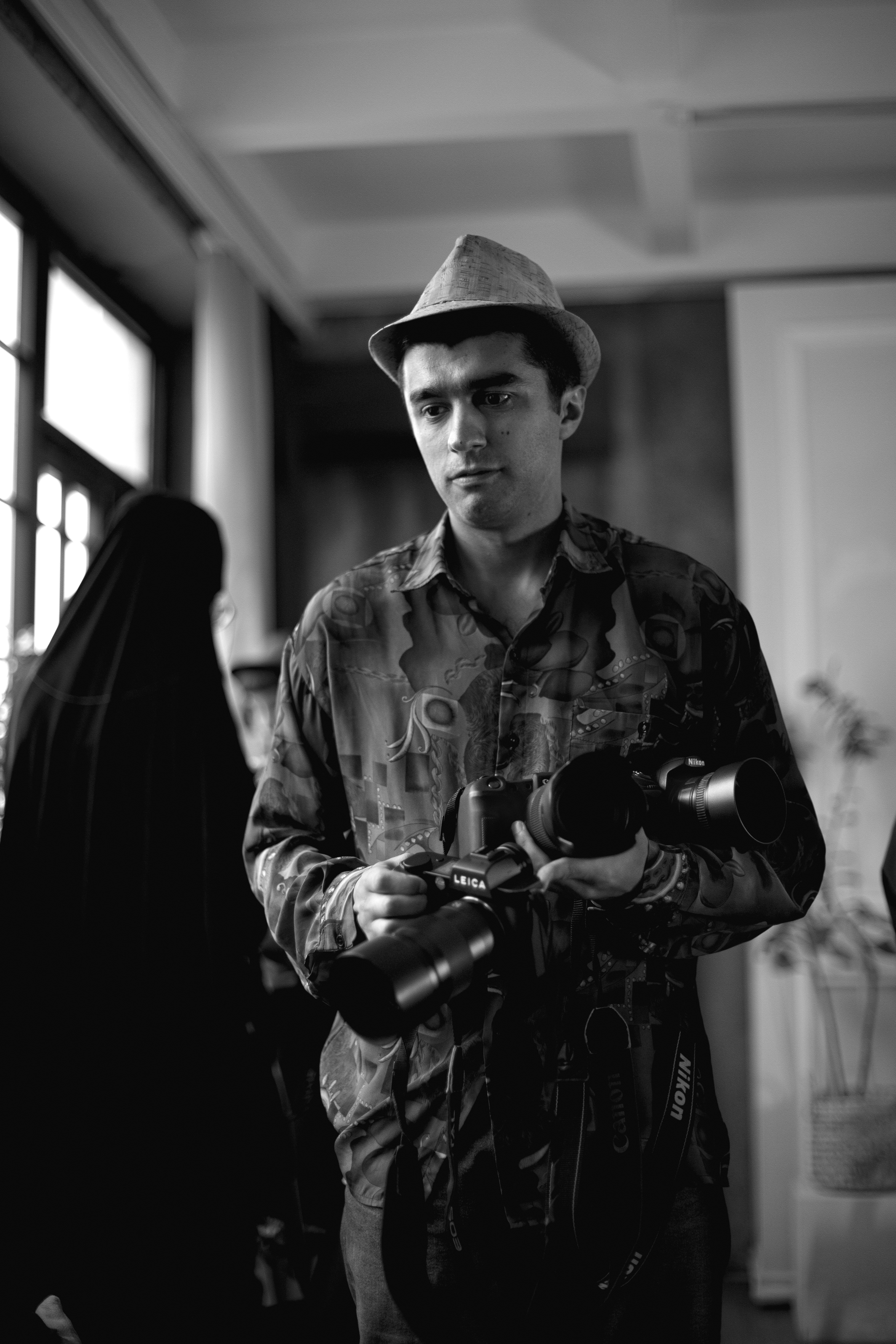 Monochrome portrait of a photographer holding a camera indoors in Baku, Azerbaijan.