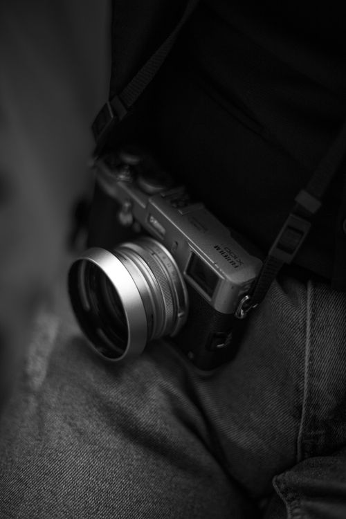 Free Black and white image of a vintage film camera with strap, showcasing classic photography equipment. Stock Photo