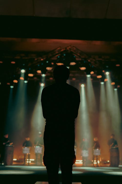 Silhouette of a Person Standing in Front of Drummers on Stage