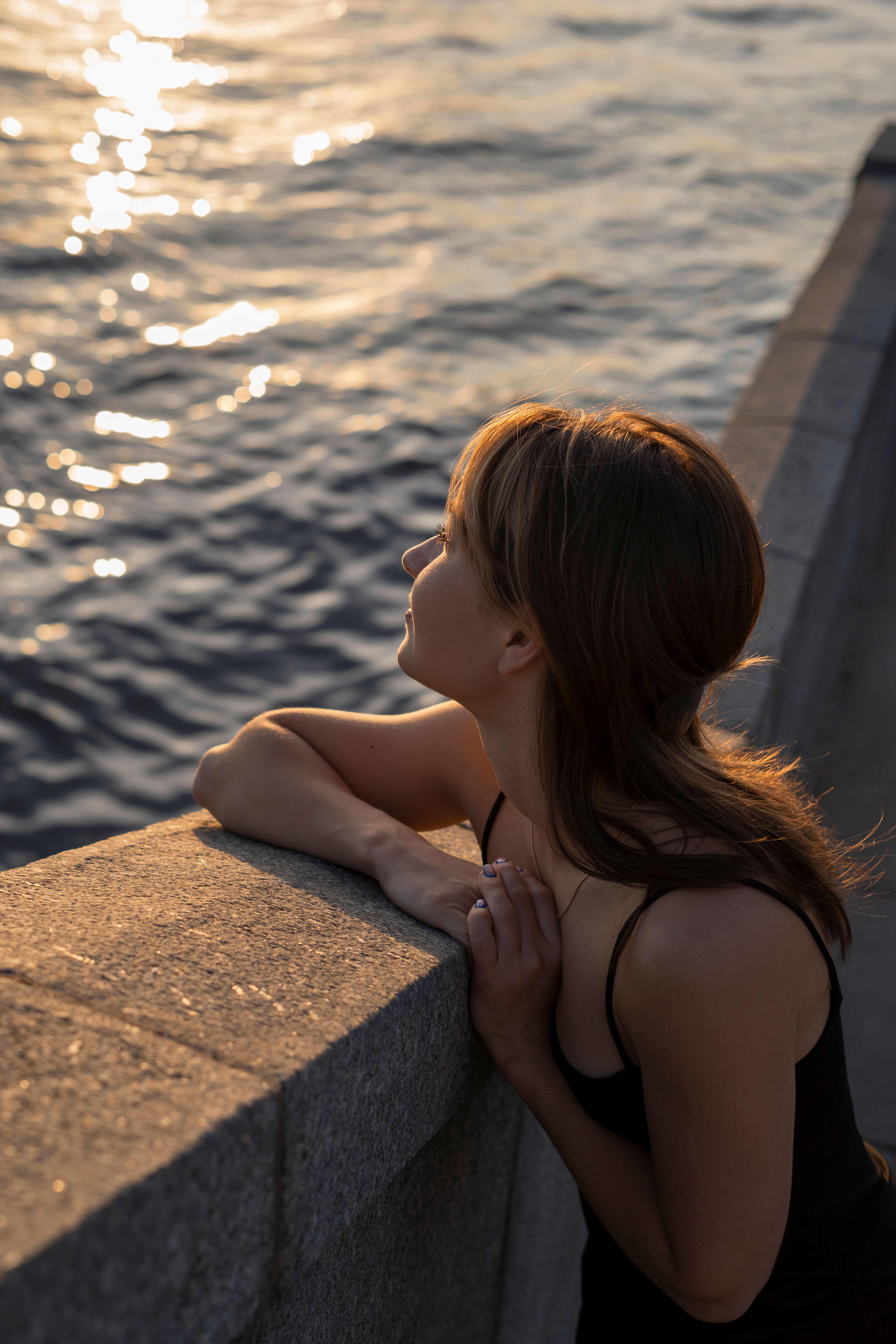 A woman looking out over the water at sunset · Free Stock Photo