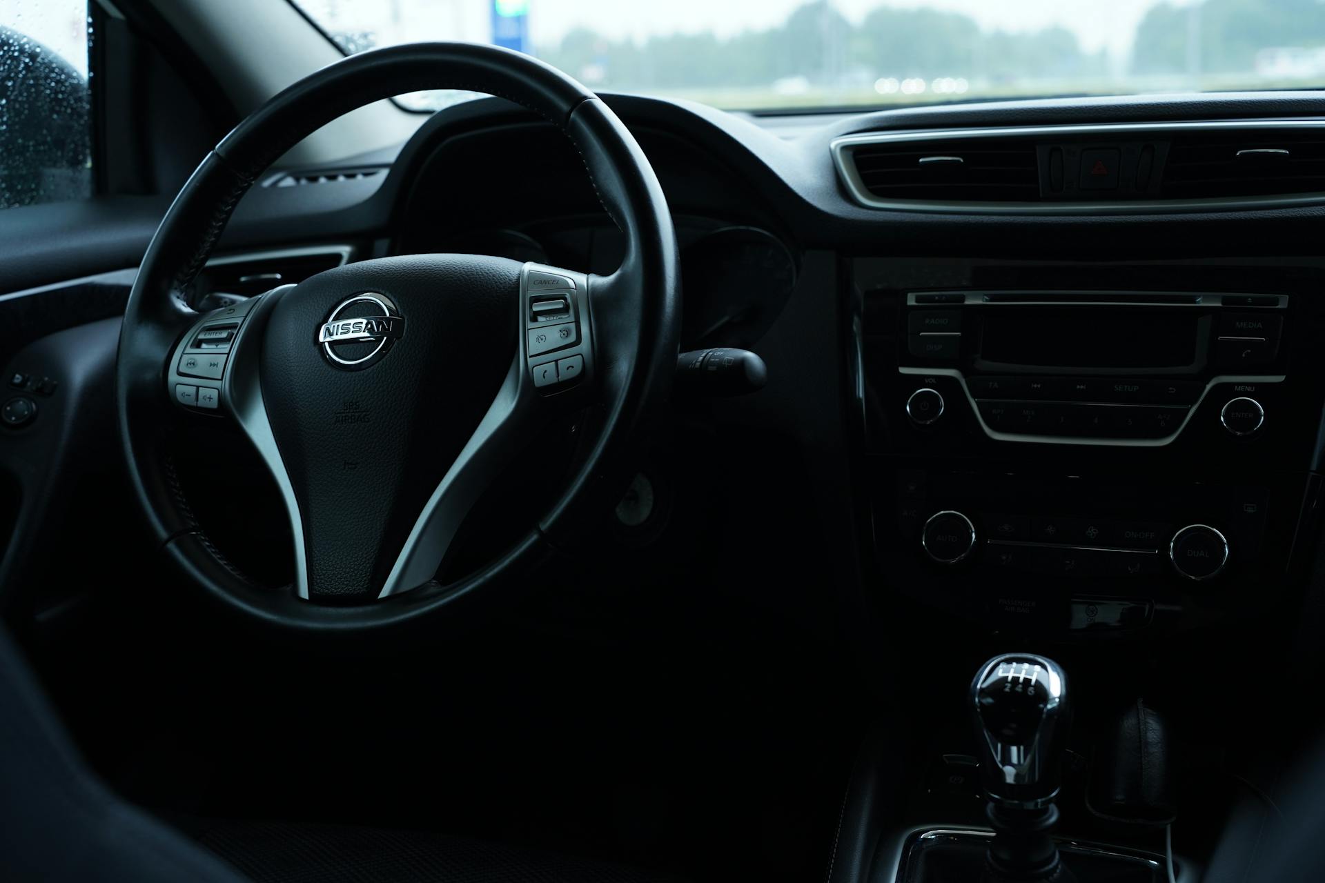 Dark interior view of a Nissan car featuring the steering wheel and dashboard details.