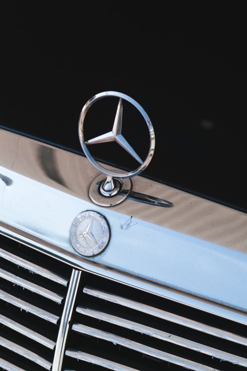 Free Close-up of a classic Mercedes grill featuring chrome emblem, highlighting vintage automotive design. Stock Photo