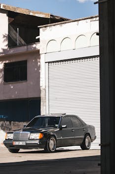 Classic black Mercedes parked on a sunlit city street with a retro look.