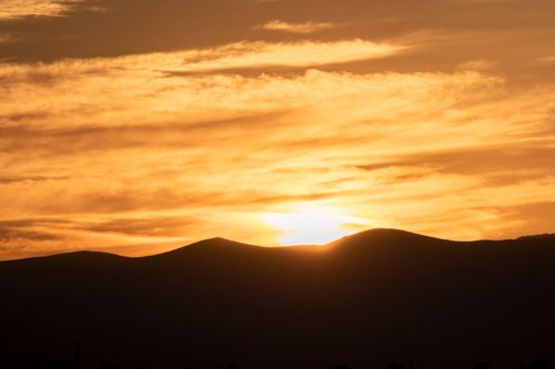 Free Golden sunset over silhouetted hills creates a tranquil view. Stock Photo